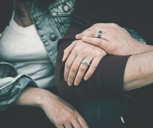 a close up photo of two people's arms linked, one hand on top of the other