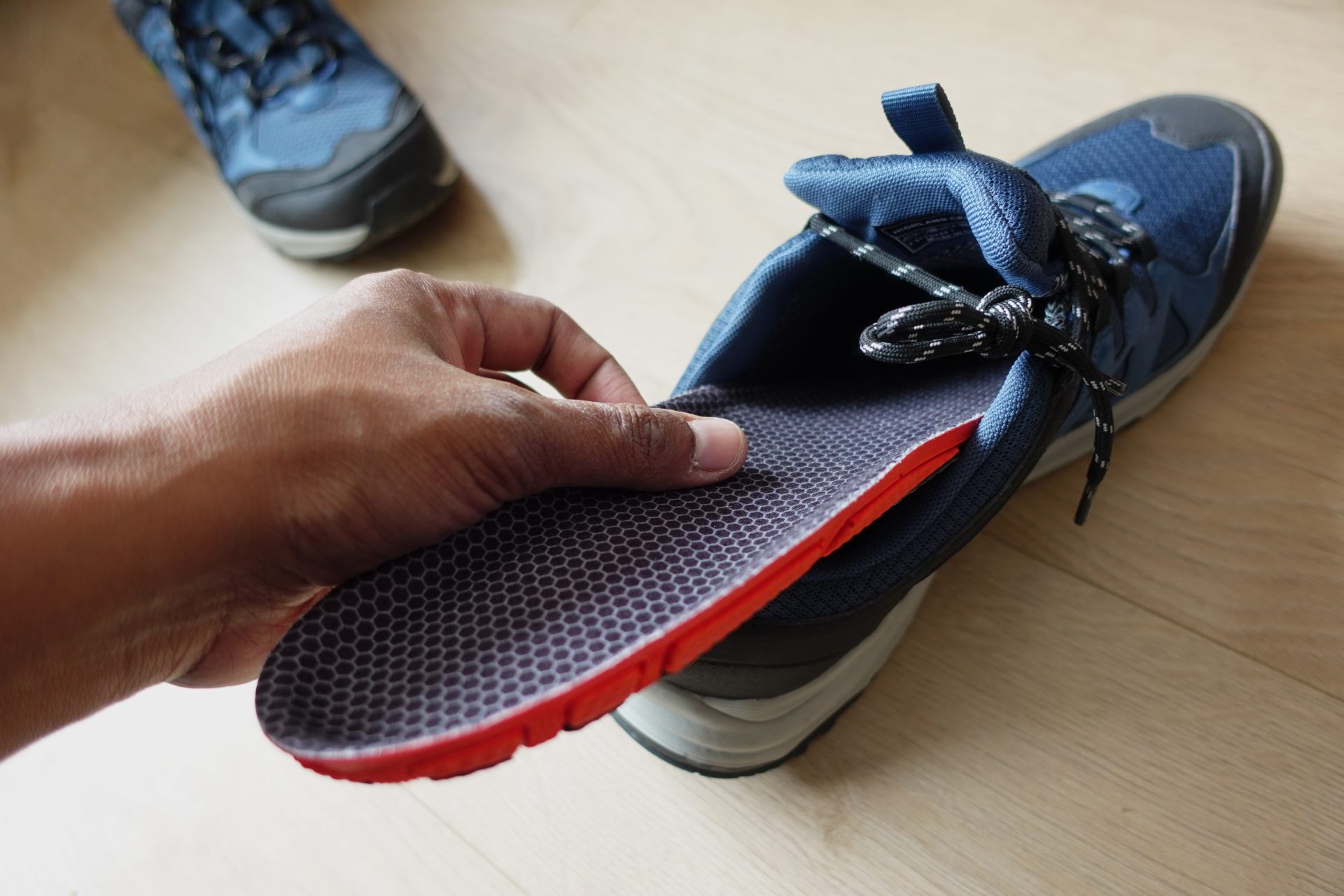 Picture of a hand putting an in-shoe orthotic into a trainer